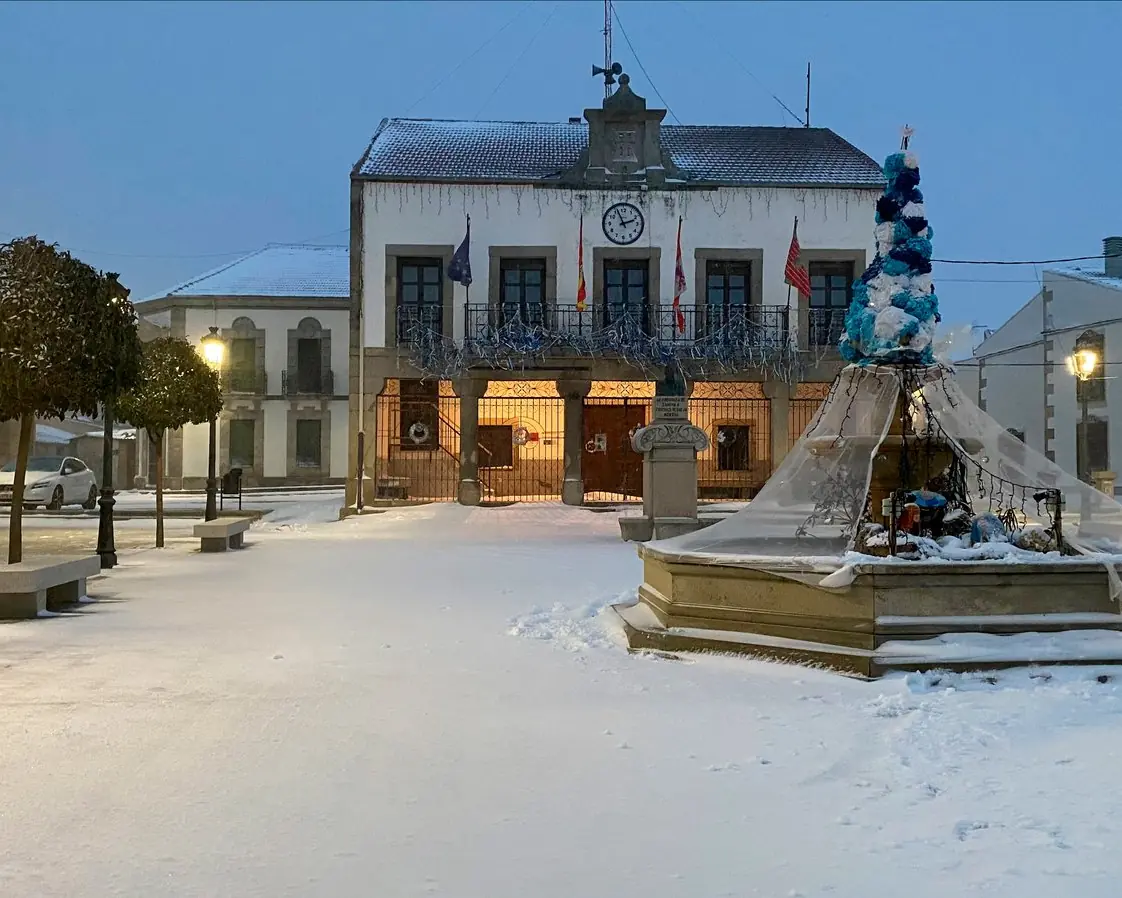 Plaza de Requejo de Bermillo de Sayago nevada al anochecer, con la fuente, las farolas y la casa consistorial