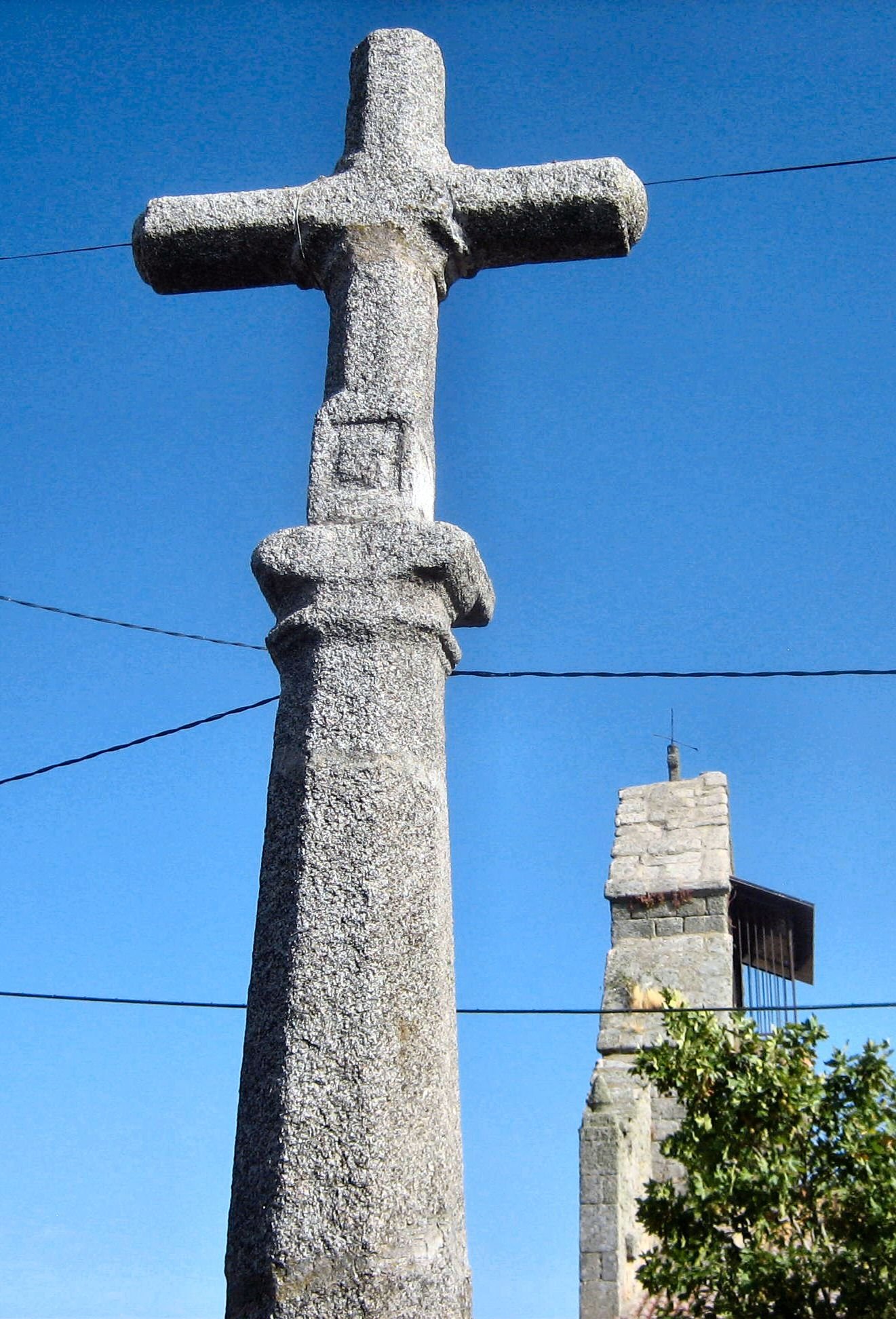 Crucero de granito junto a la iglesia de Villamor de la Ladre, sobre cielo azul